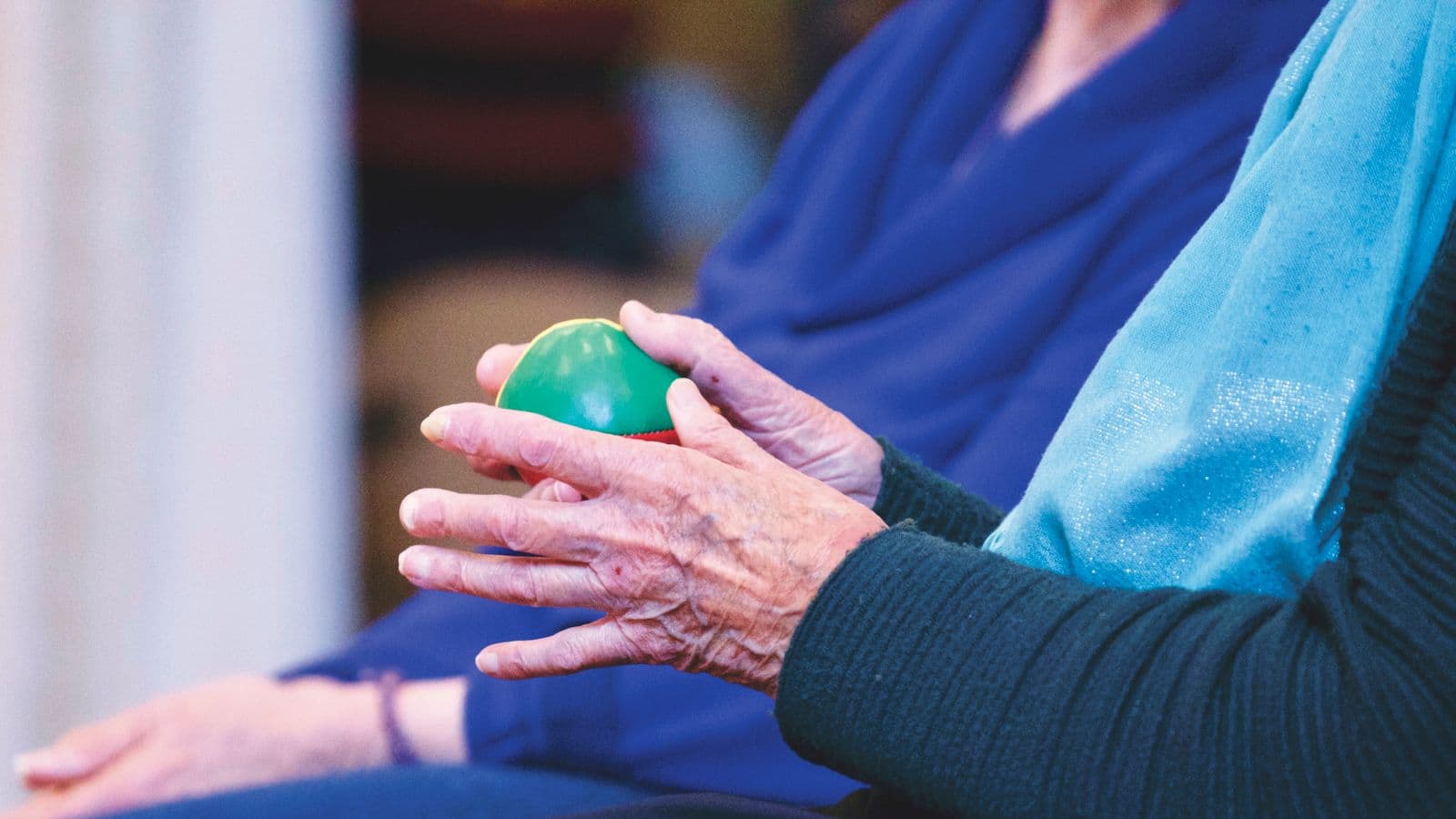 Manos de una persona mayor sosteniendo una pelota de terapia